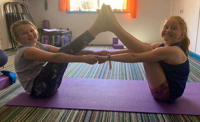 STRETCHING AHEAD OF CLASS: Isabel Bolidston and Isabel Mannes practice a partner boat pose ahead of a yoga fundraiser over the October long weekend. PHOTO: Supplied