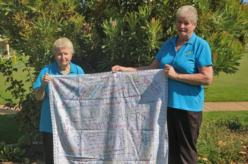 CELEBRATING HISTORY: Sunshine Club secretary/treasurer Jean Jones and president Sue Porter hold up one of the club's traditions - a tablecloth detailing the names of all the club's former and current members. PHOTO: Calhan Behrendt